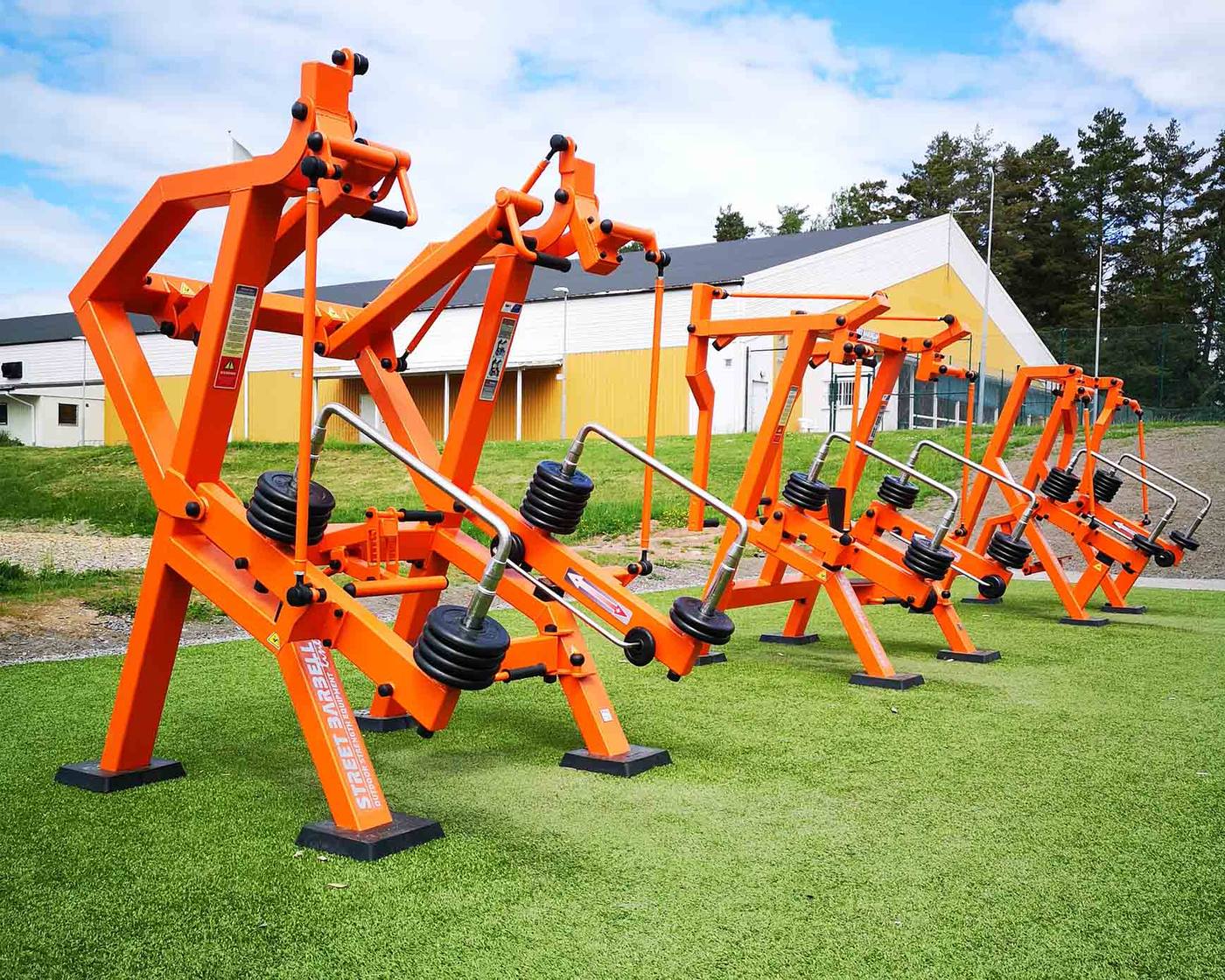 A row of orange StreetBarbell outdoor strength machines